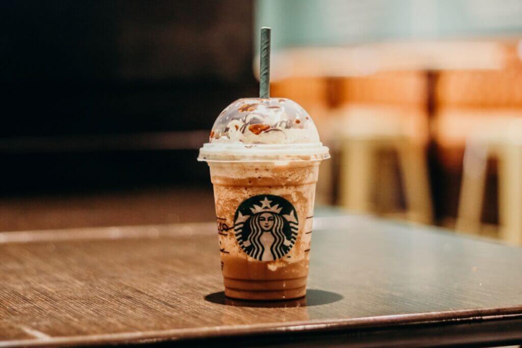 A cup of starbucks coffee with a paper straw in it.